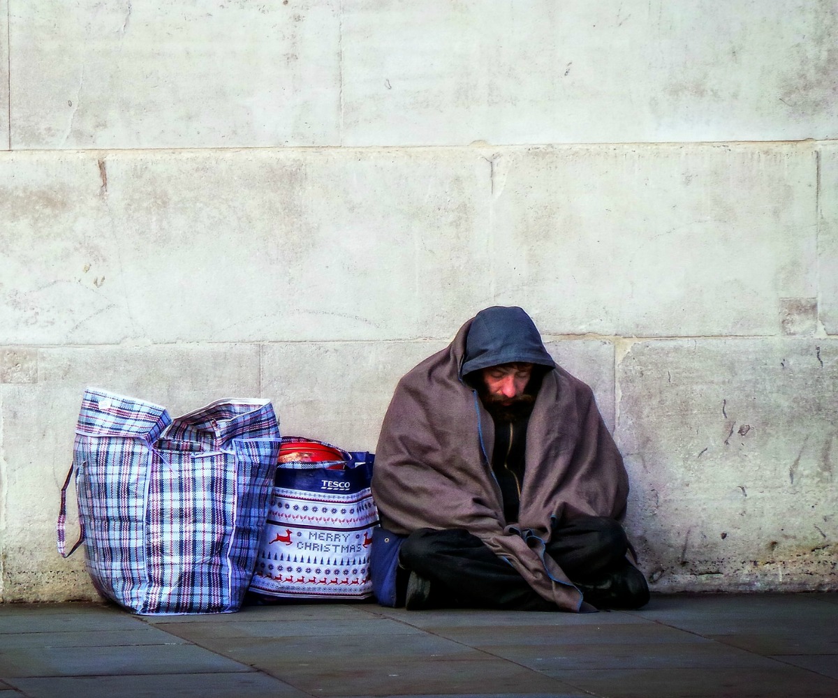 obdachloser-vor-mauer-sitzend