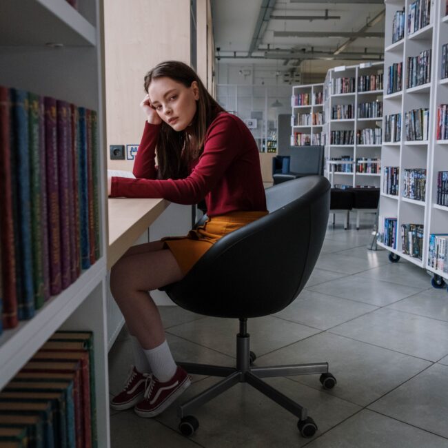Ein Mädchen sitzt in einer Bibliothek und versucht zu lernen