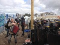 Flüchtlingscamp Calais Mann mit Akkordeon vor Polizei