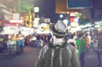 Young Asian traveling backpacker in Khaosan Road night market in evening in Bangkok, Thailand