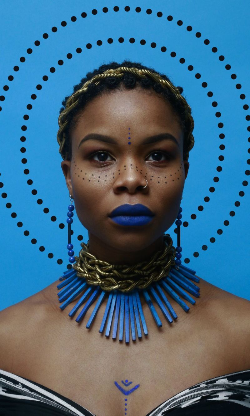yannis guiba- Afrikansiche Frau mit blauem Schmuck vor blauem Hintergrund