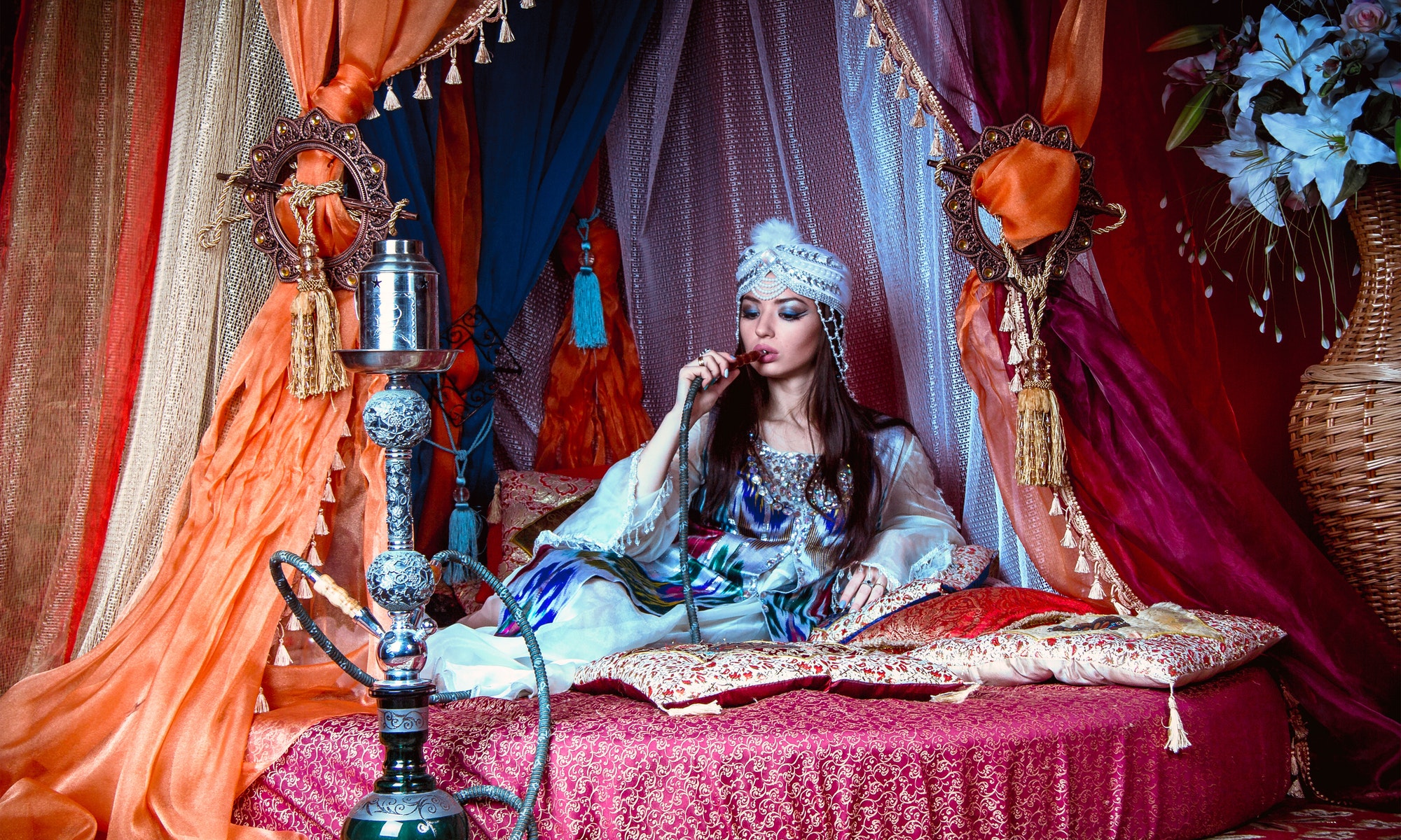 Shisha rauchen- orientalische Frau auf Bett mit Baldachin