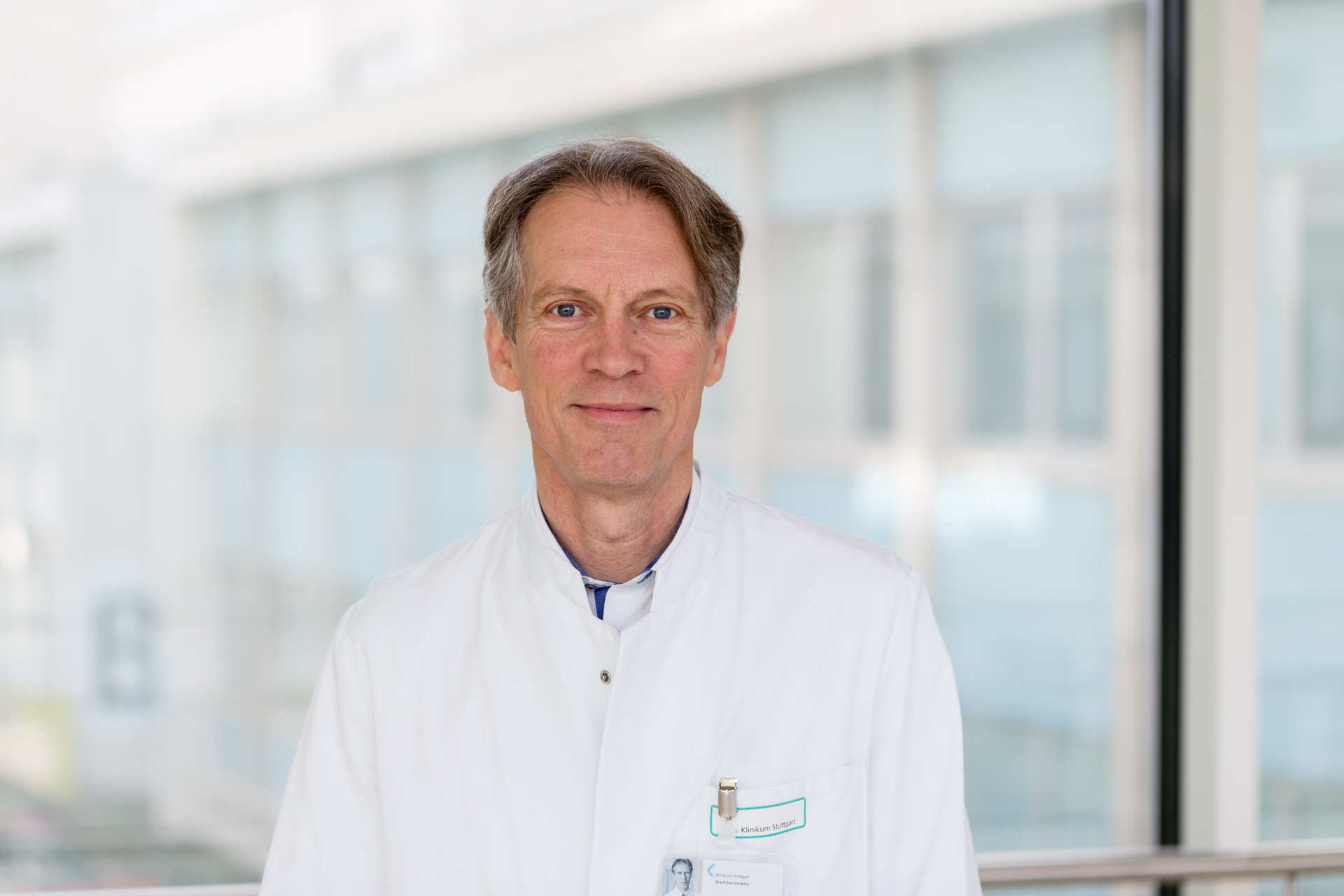 Das Bild zeigt den Arzt Prof. Dr. Ulrich Karck. Er ist mittleren Alters, hat braun-gräuliche Haare und trägt einen weißen Kittel.