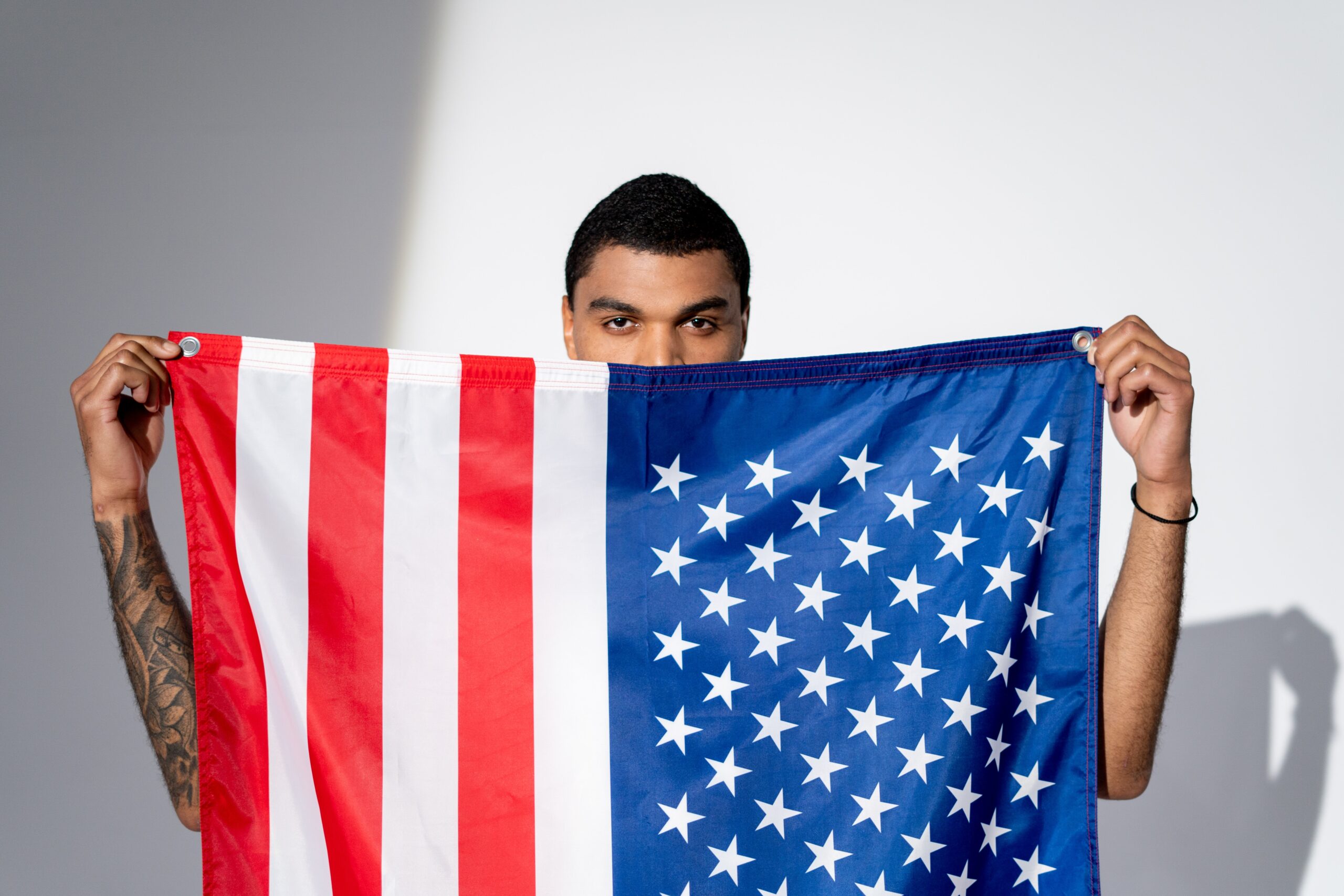 Ein Mann hält eine USA-Flagge vor seinen Körper und vor Teile seines Gesichts.