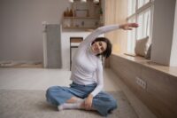 Eine junge Frau macht Dehnübungen in ihrer Wohnung