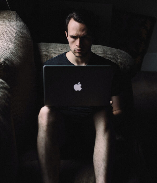 Ein Mann sitzt in der Dunkelheit vor einem Laptop