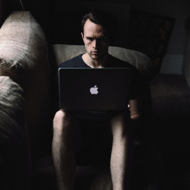 Ein Mann sitzt in der Dunkelheit vor einem Laptop