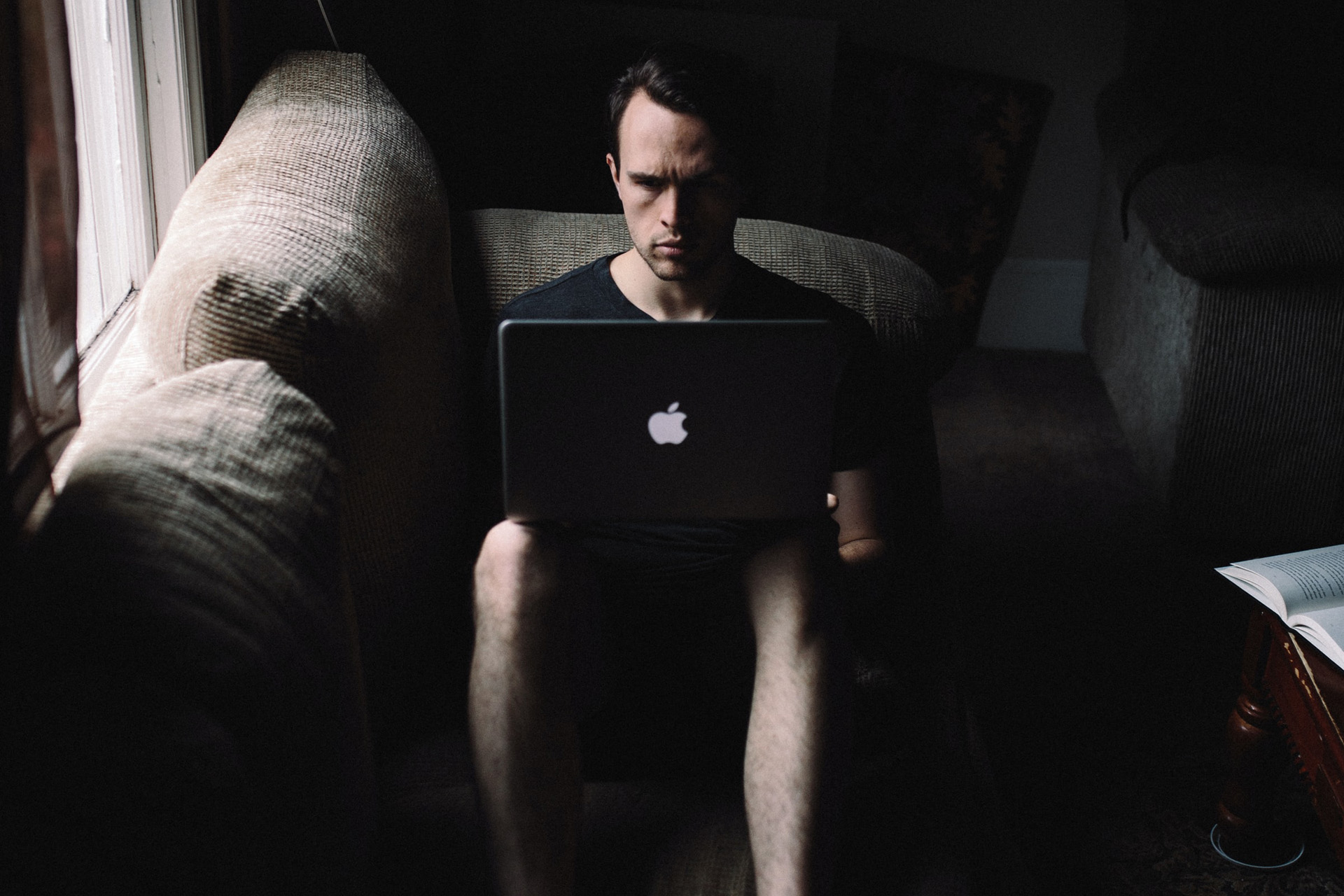 Ein Mann sitzt in der Dunkelheit vor einem Laptop