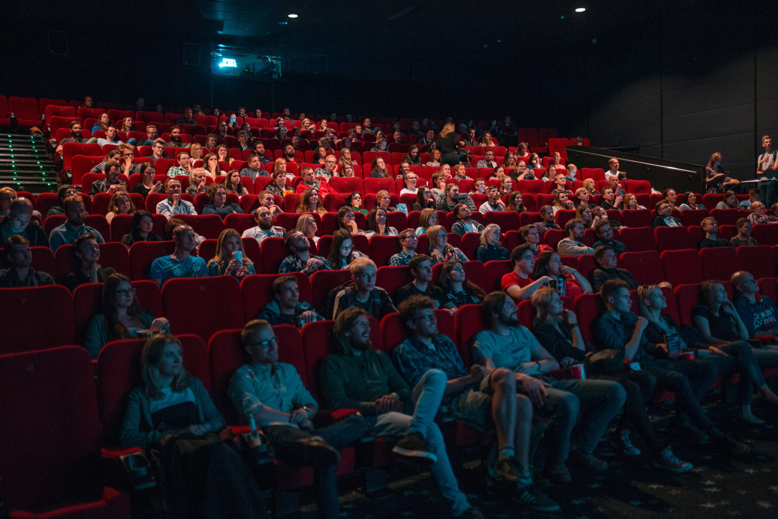 Menschen sitzen in einem Kinosaal und schauen zur Leinwand.