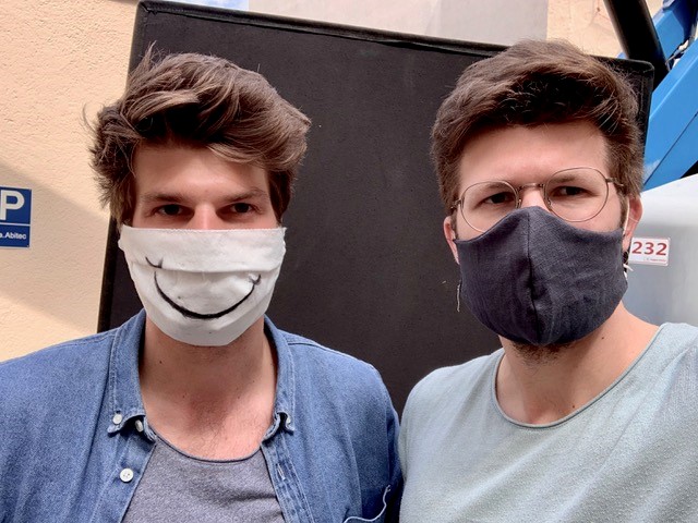 Die Brüder Kevin und Toby Schmutzler schauen in die Kamera und tragen eine Mund-Nasen-Maske