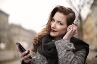 Frau lächelt mit Kopfhörern und Smartphone