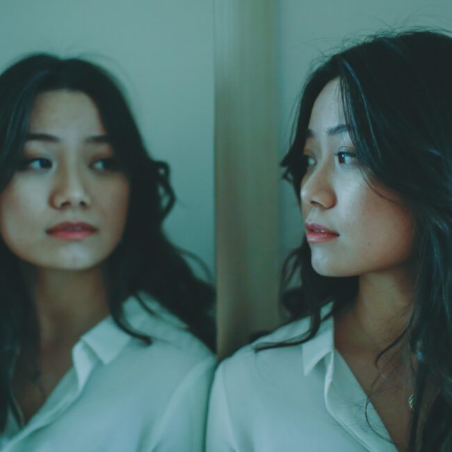 Eine Frau schaut nachdenklich in einen Spiegel