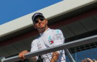 Formel-1-Fahrer Lewis Hamilton steht an einem Geländer und lächelt