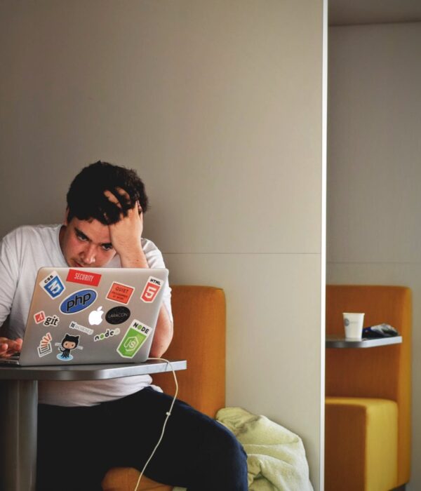Ein junger Mann sitzt an einem Tisch vor dem Laptop und lernt.
