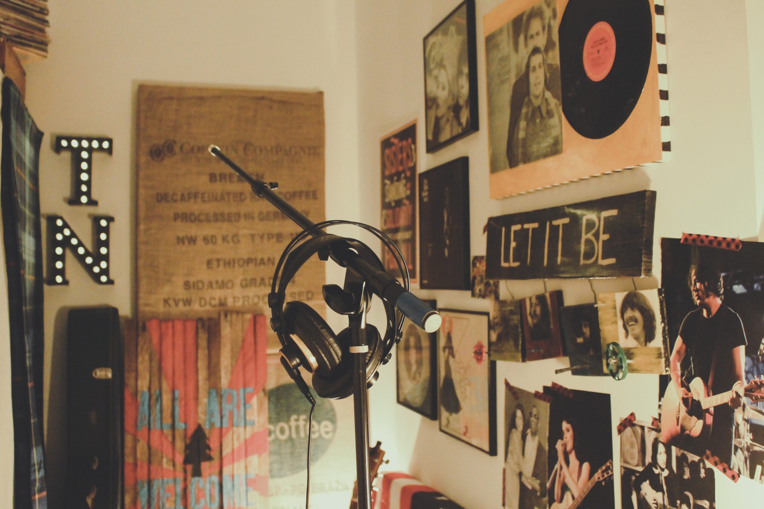 Ausschnitt von Zimmer mit vielen Bildern an der Wand und Mikrofon plus Kopfhörer