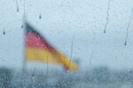 Eine Deutschlandflagge durch eine verregnete Scheibe betrachtet