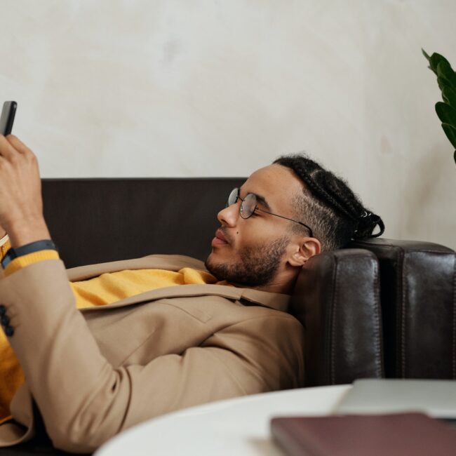 Mann liegt mit Smartphone auf dem Sofa