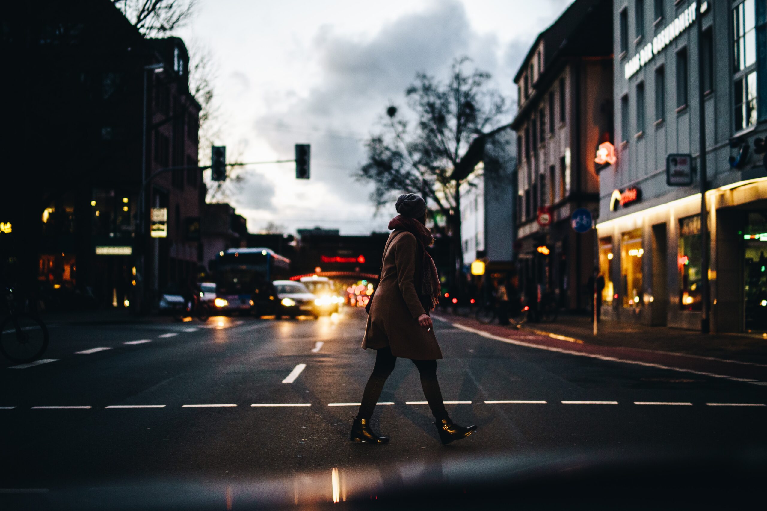 Eine Frau überquert abends die Straße