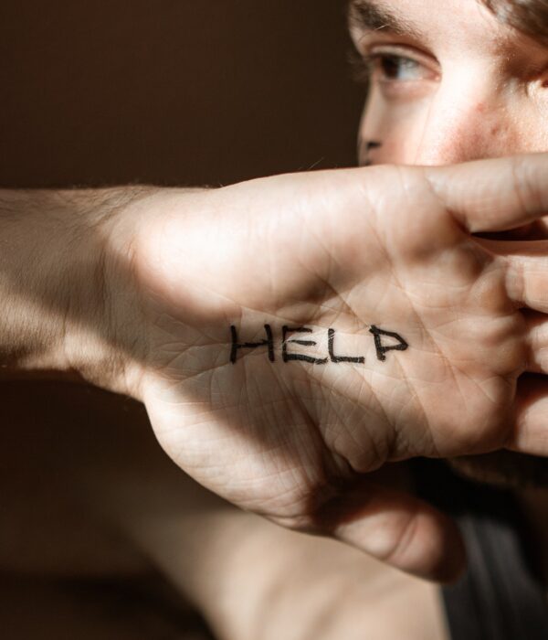 Mann der seine Hand mit der Aufschrift "Help" vors Gesicht hält