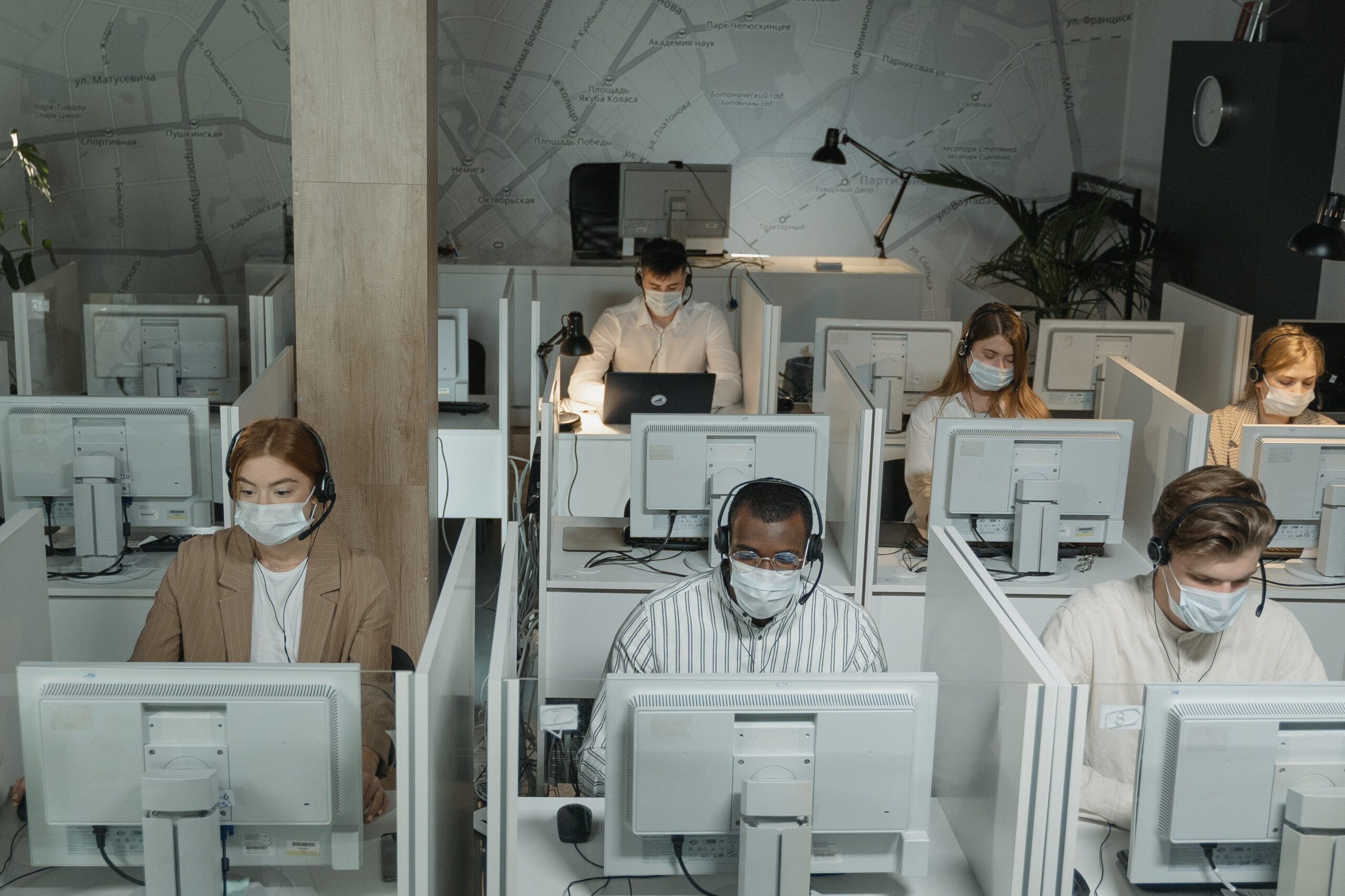 Mehrere Menschen sitzen mit Masken in einem Großraumbüro