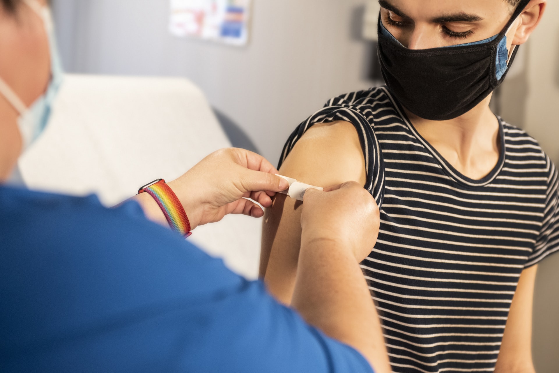 Junger Mann bekommt ein Pflaster auf den Arm nach einer Impfung