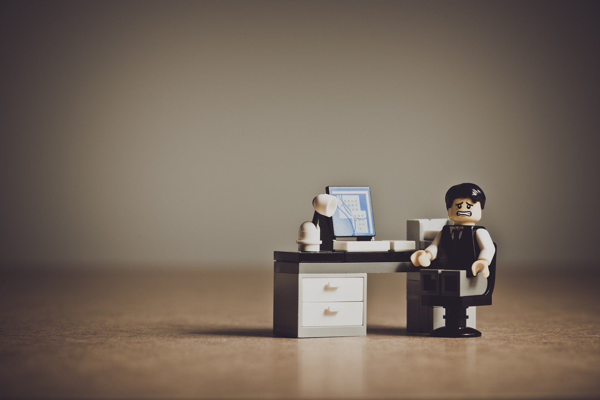 Trauriges Arbeiter-Lego-Männchen sitzt am Schreibtisch