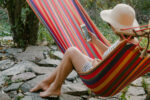 Eine Frau liegt entspannt in der Hängematte und liest auf ihrem Smartphone. Bild: Pexels