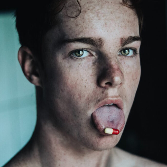 Mann hat eine Pille auf der Zunge. Bild: Unsplash