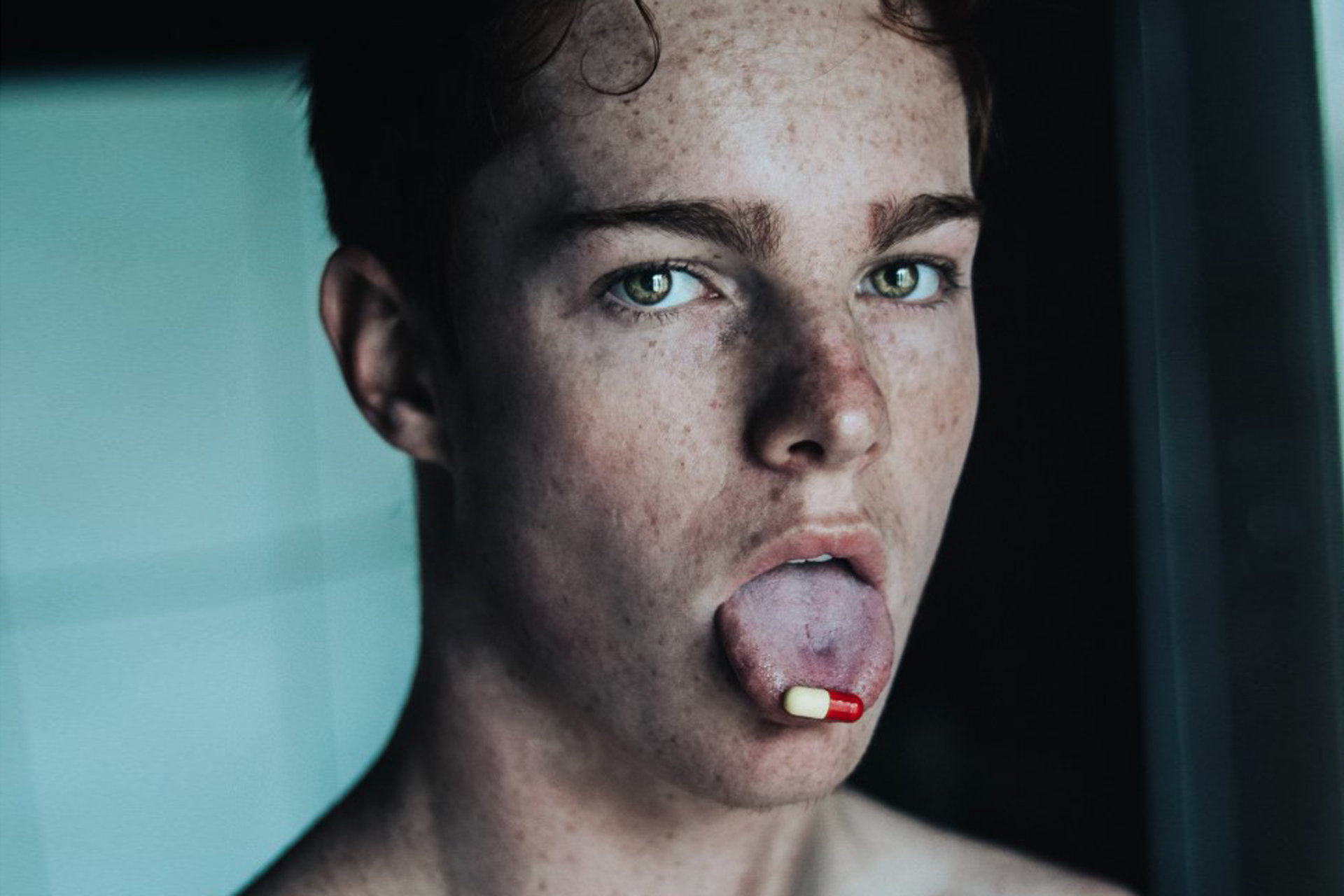 Mann hat eine Pille auf der Zunge. Bild: Unsplash