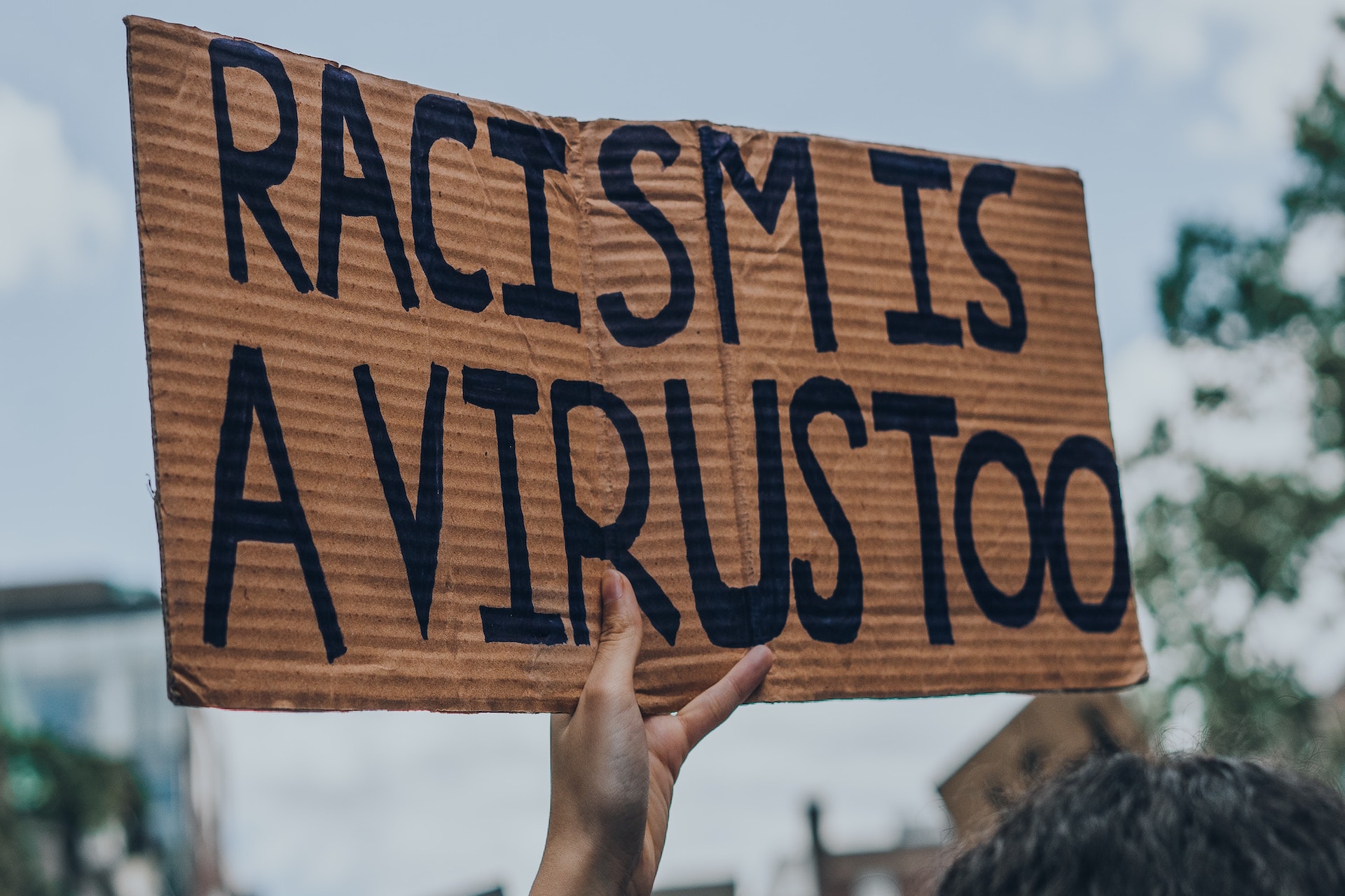 Ein Schild mit der Aufschrift: "Racism is a Virus too".