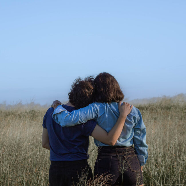Zwei Menschen stehen auf einer Wiese und umarmen sich. Bild: Pexels