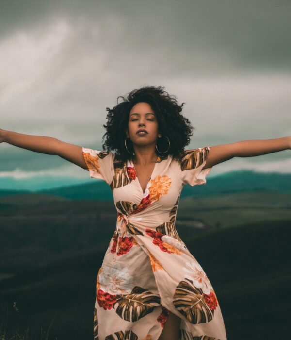 Frau steht auf einem Berg und breitet die Arme aus