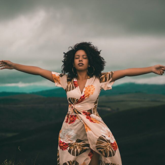 Frau steht auf einem Berg und breitet die Arme aus