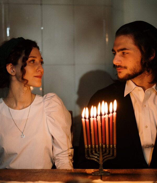 Jüdisches Paar sitzt vor Chanukka-Leuchter. Bild: Pexels