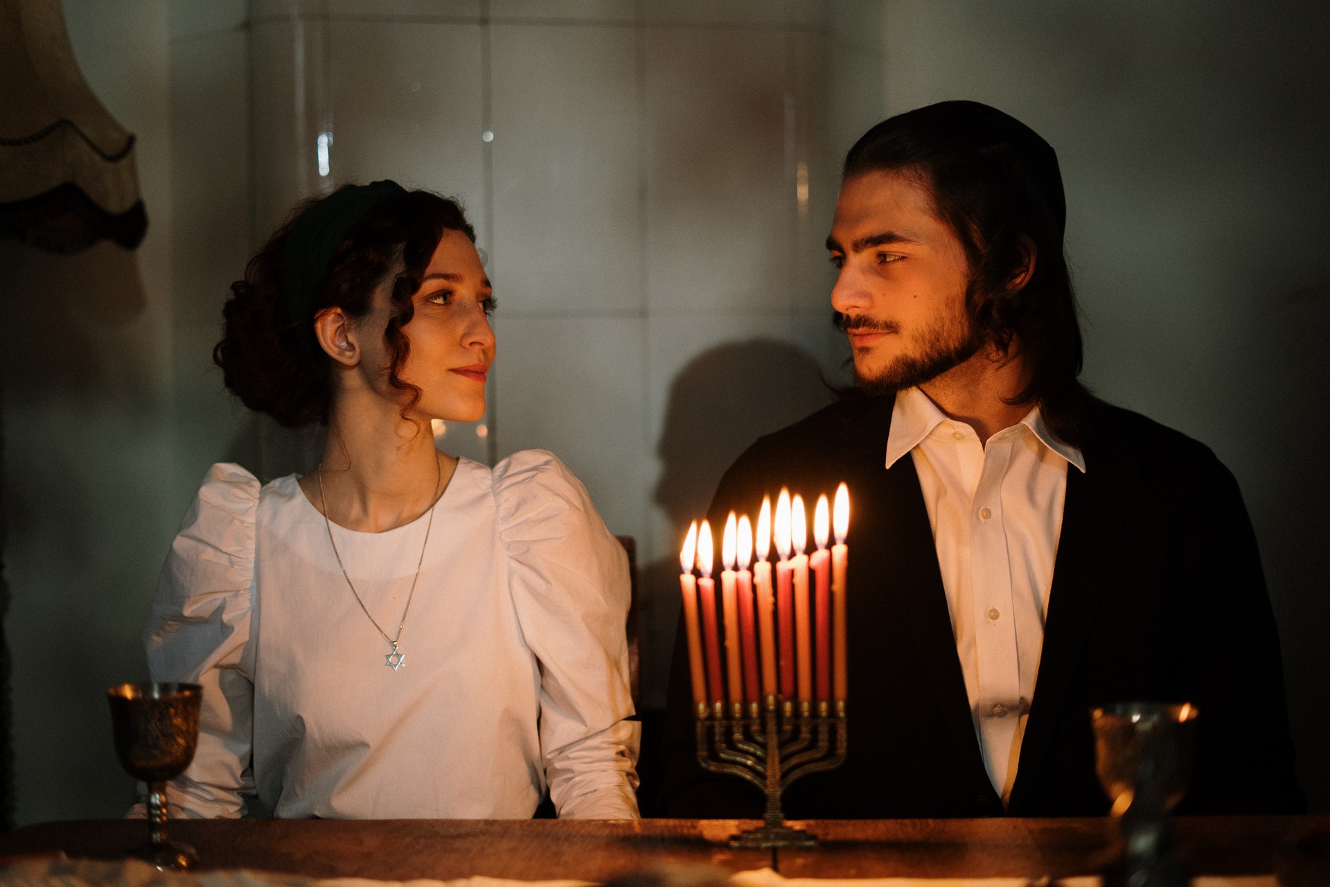 Jüdisches Paar sitzt vor Chanukka-Leuchter. Bild: Pexels