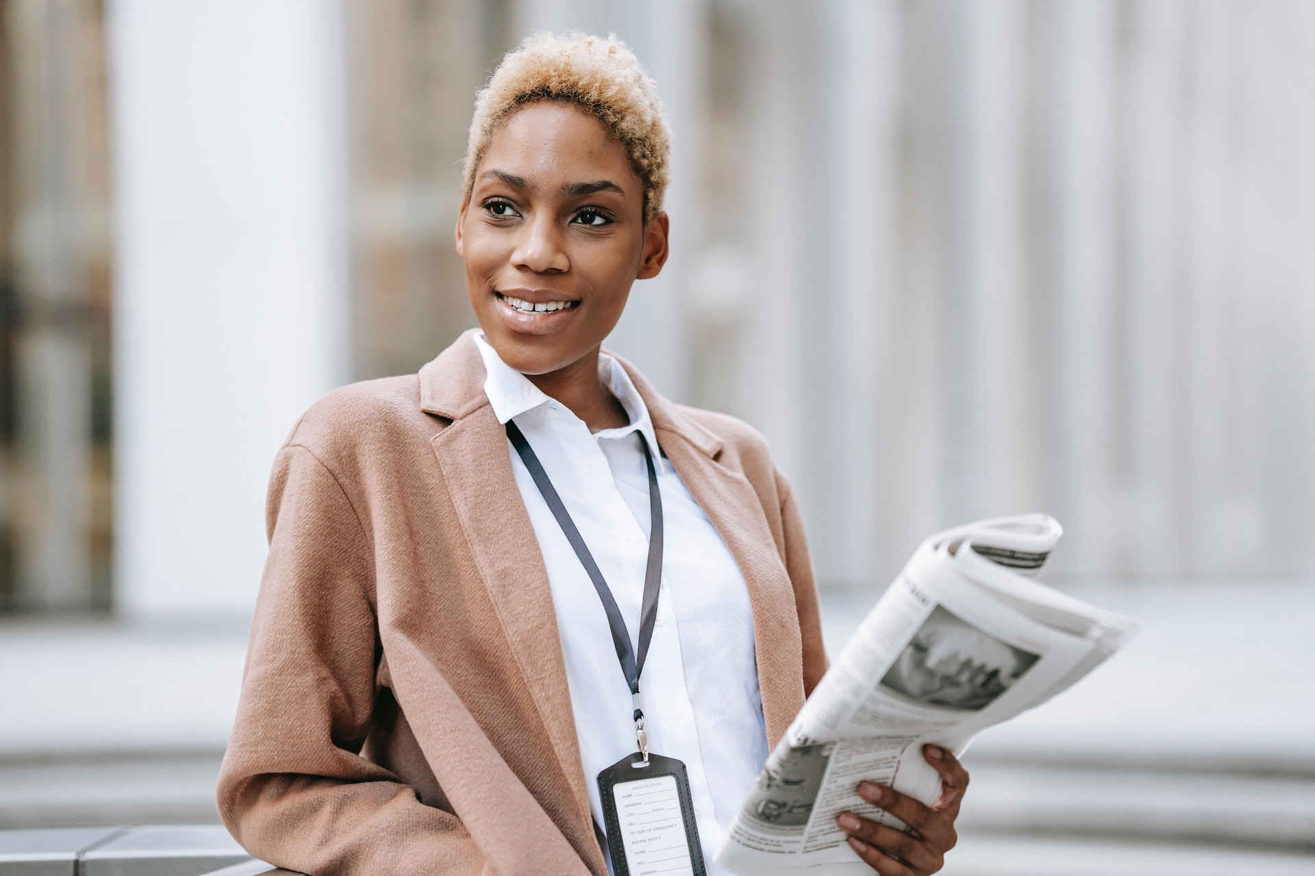 Frau lächelt mit Zeitung in der Hand. Bild: Pexels