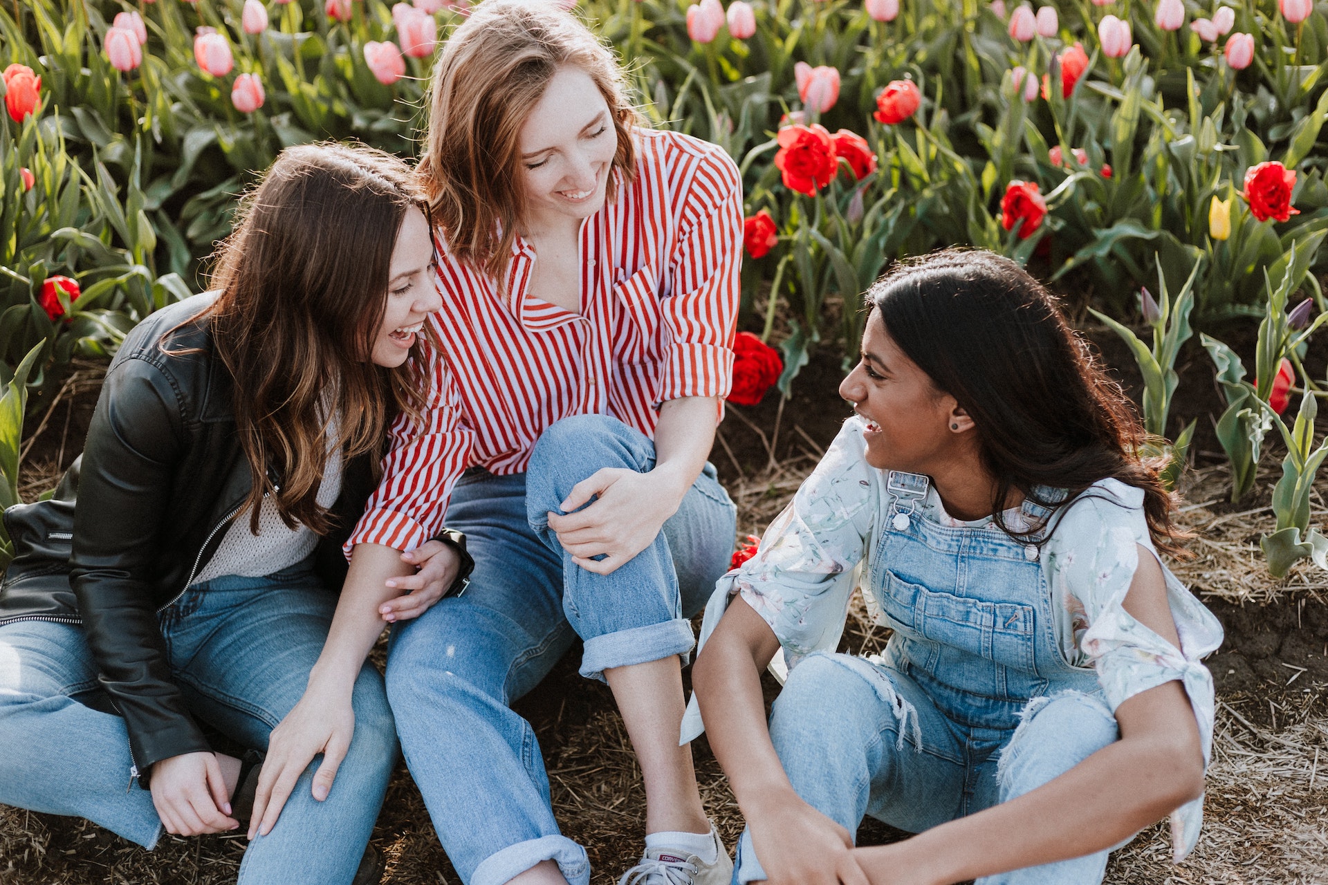 Drei Frauen sitzen in einem Feld und lachen zusammen.