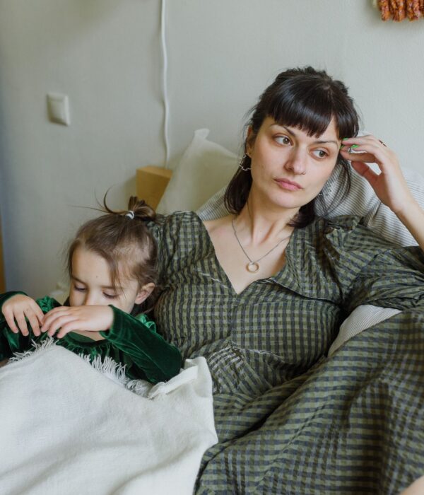 Eine Mutter sitzt mit ihrem Kind auf einem Bett und guckt traurig zur Seite. Bild: Pexels