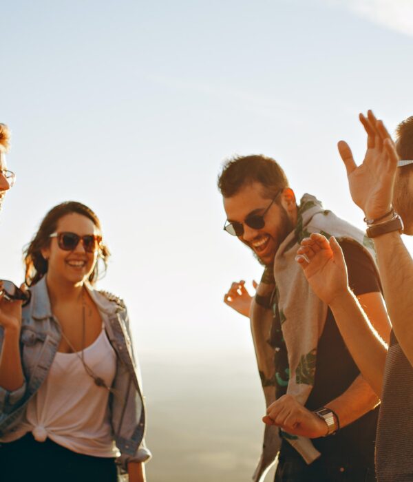 Vier lachende Menschen vor blauem Himmel