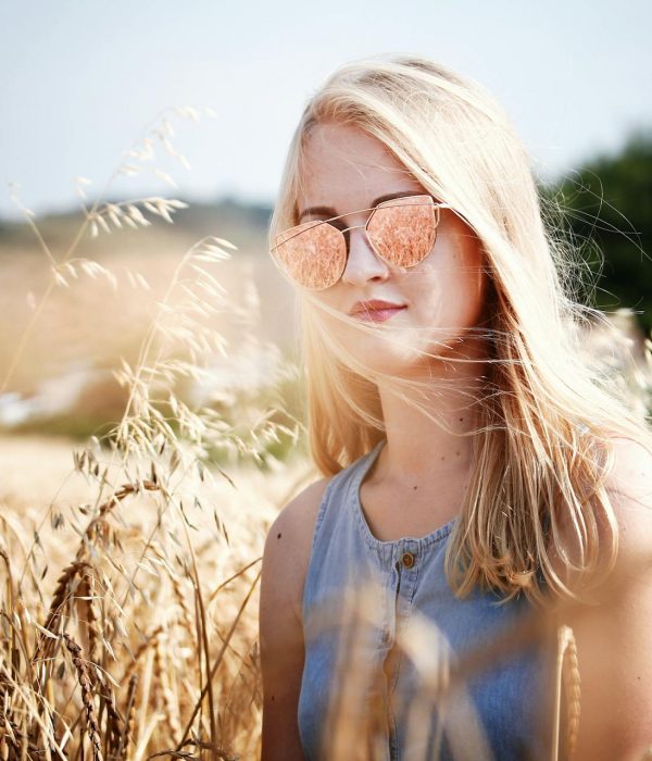 Frau mit Sonnenbrille, die in Weizenfeld steht