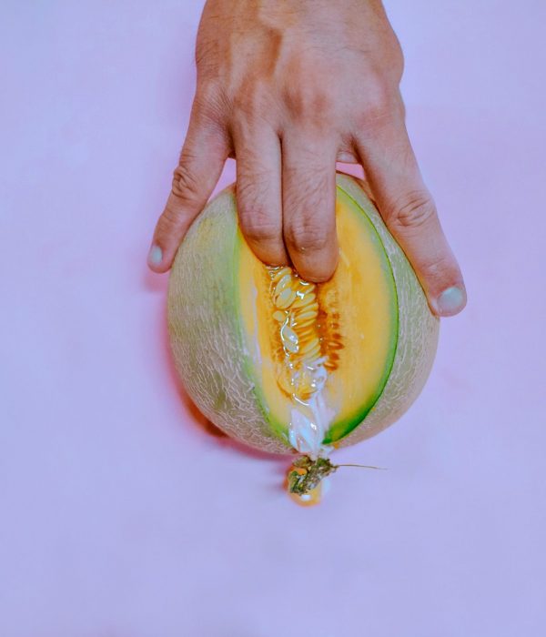 Bild einer Papaya die eine Vagina repräsentieren soll. Mit zwei Fingern in der Frucht und weißer Flüssigkeit die unten raus fließt.
