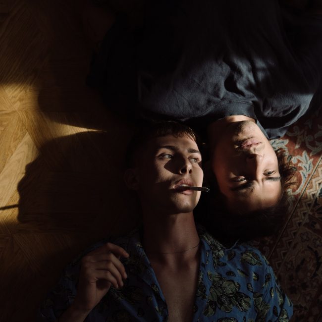 Zwei Menschen die zusammen auf den Boden liegen, einer raucht