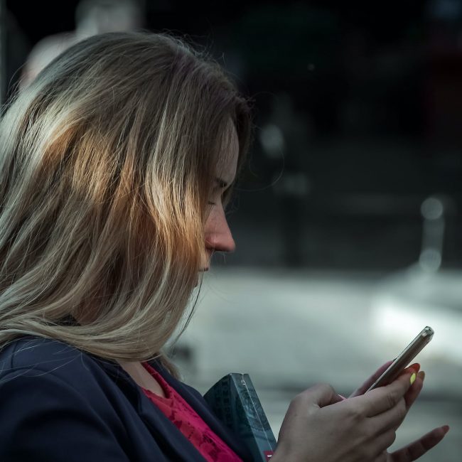 Junge Frau schaut auf ihr Handy